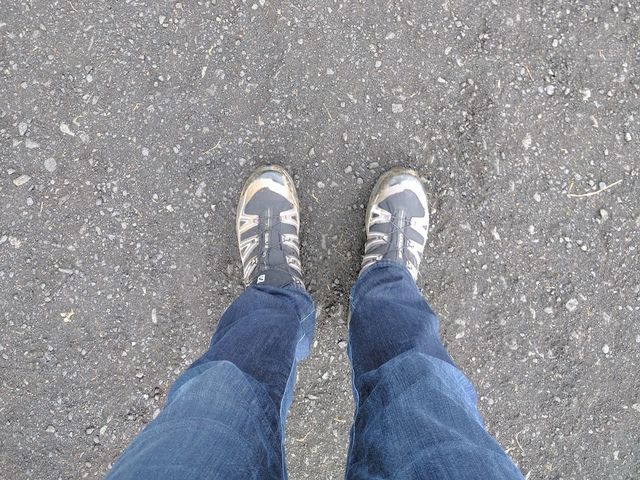 Looking down at hiking boots on black volcanic sand in Iceland.