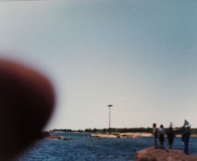 'An osprey nesting platform in the distance, with the photographer’s thumb obscuring the lower right of the frame.'